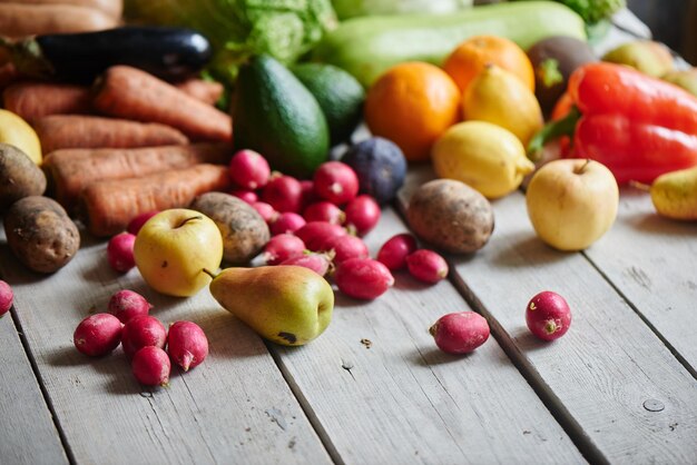 Eine Reihe von reifen gesunden Lebensmitteln, bestehend aus Gemüse und Obst, die auf dem Holztisch liegen, Nahaufnahme