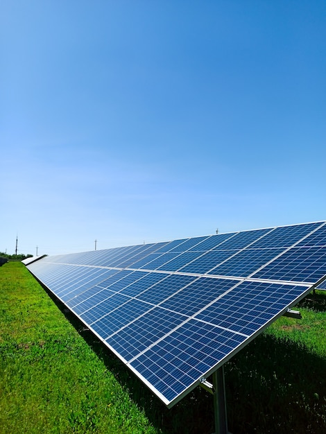 Eine Reihe von Sonnenkollektoren steht auf einer grünen Wiese vor dem blauen Himmel. Ein Symbol für saubere Energie, Sorge um die Umwelt, ein Konzept.