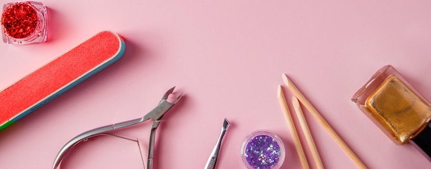 Eine Reihe von Werkzeugen für Maniküre und Nagelpflege auf rosa Hintergrund Arbeitsplatz in einem Schönheitssalon