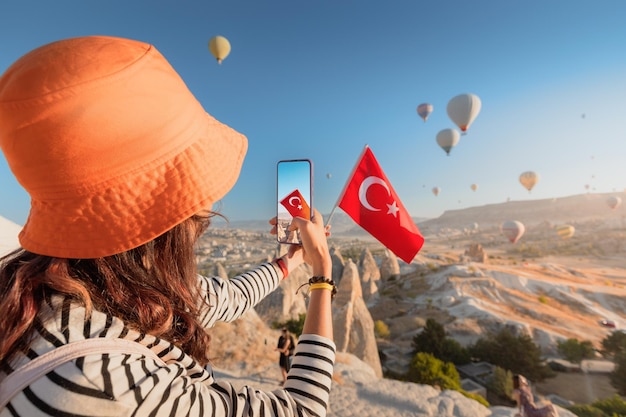 Foto eine reisebloggerin fotografiert fliegende luftballons in kappadokien und die türkische flagge als social-media-influencerin