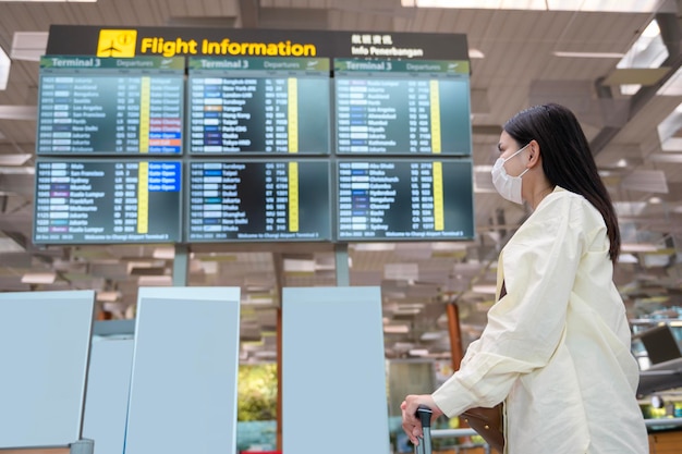 Eine Reisende Frau trägt eine Schutzmaske auf dem internationalen Flughafen