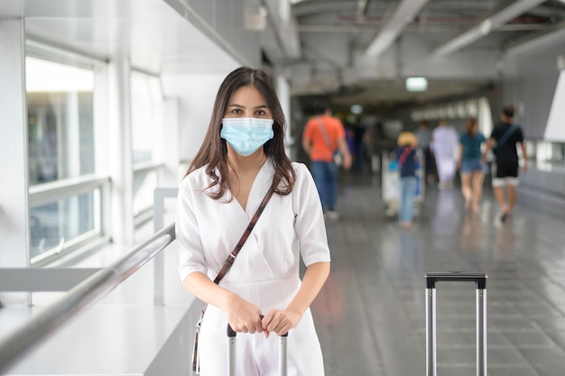 Eine reisende Frau trägt Schutzmaske auf dem internationalen Flughafen, reist unter Covid-19-Pandemie,