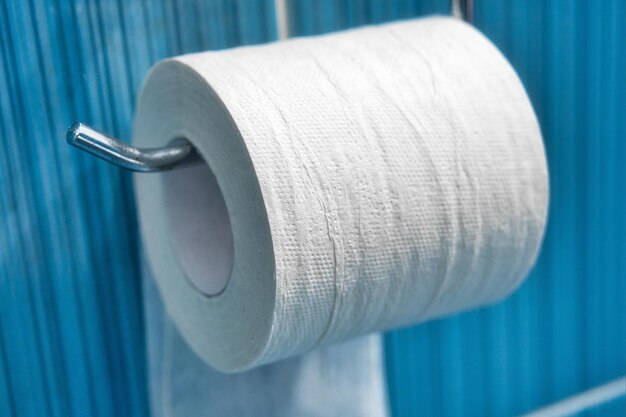 Foto eine rolle toilettenpapier hängt auf einem halter an einer blauen wand.