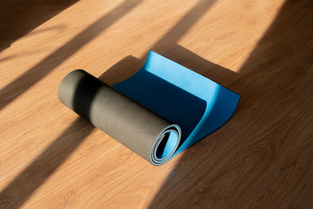 Eine Rolle Yogamatte auf dem Holzboden, Training im Fitnessstudio, Sportgeräte