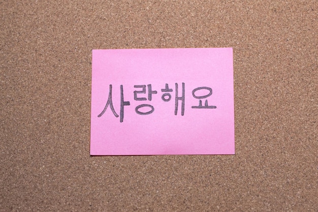 Foto eine rosa klebebandkarte mit einer ich liebe dich-botschaft auf koreanisch auf einer korktafel