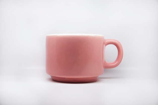 Eine rosa Tasse, die auf einem weißen Tisch steht