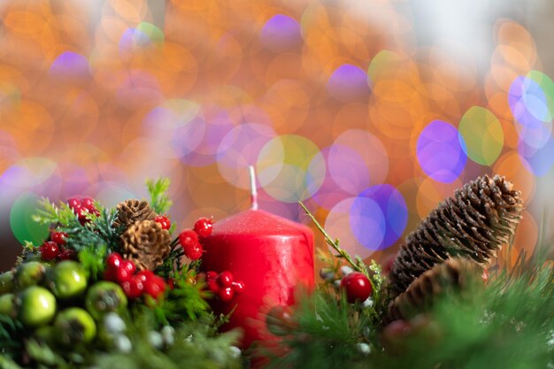 Eine rote Kerze in einem Weihnachtsbaum Dekorationen für die Ferienzeit Auf dem zweiten Herrn das flackernde Bokeh der Weihnachtenbaum Lichter