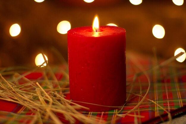 Eine rote Kerze wird vor einem weihnachtlichen Hintergrund angezündet.
