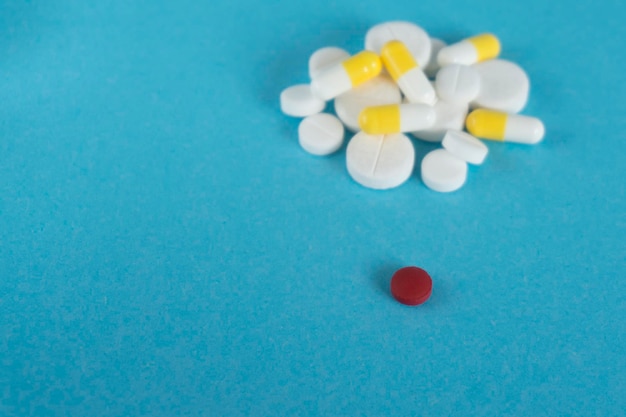 Eine rote und viele weiße Pillen auf blauem Hintergrund Konzept der Medikamente