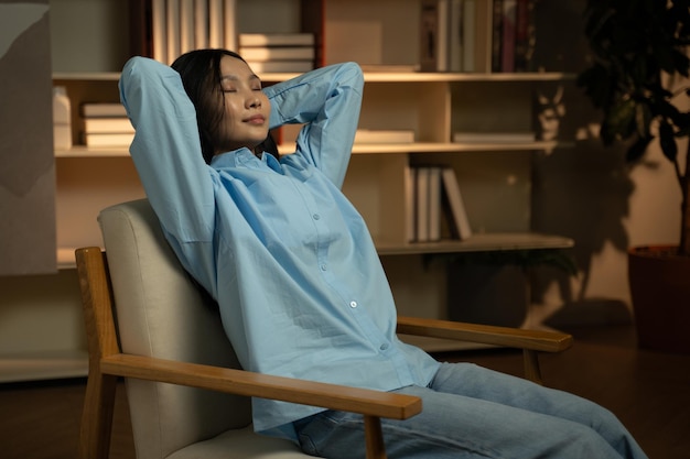 Eine ruhige asiatische Frau entspannt sich in einem gemütlichen Stuhl in einem gut beleuchteten Raum