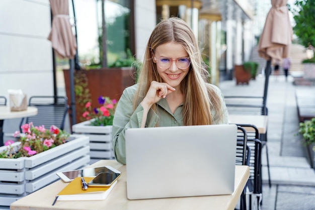 Eine ruhige junge Frau benutzt einen Laptop in einem hellen Raum, der den Inbegriff von konzentrierter Arbeit darstellt