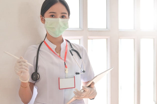 Eine Ärztin, die eine Maske trägt, hält eine Patientenakte mit Stethoskop.