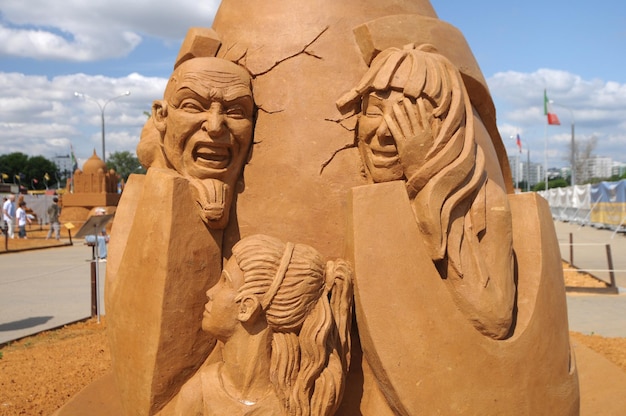 Eine Sandskulptur von zwei Frauen und einer Frau mit einem Gesicht darauf.