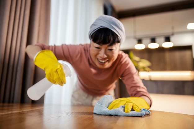 Eine saubere japanische Frau putzt zu Hause die Oberflächen