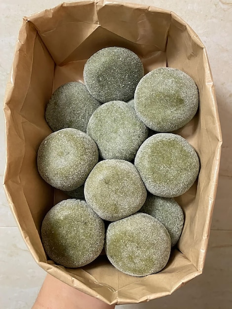 Eine Schachtel grüner Mochi-Teig mit einer braunen Papiertüte.