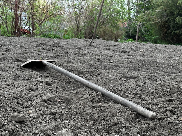 Eine Schaufel liegt im Dreck vor einem Haus.