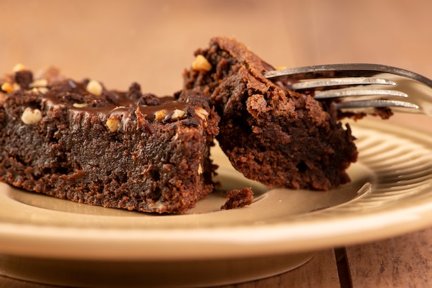Eine Scheibe Brownie auf einem Teller auf Holztisch.