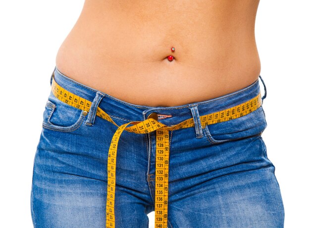 Eine schlanke junge Frau in Jeans mit einem Maßband nach einer erfolgreichen Diät