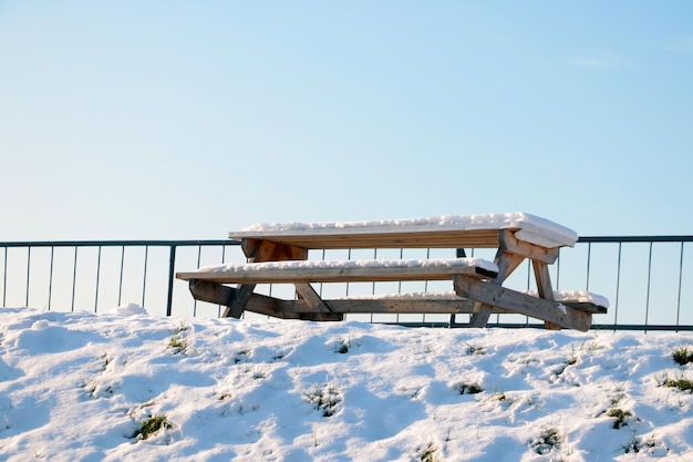Eine schneebedeckte Bank und ein Tisch in einem Winterpark