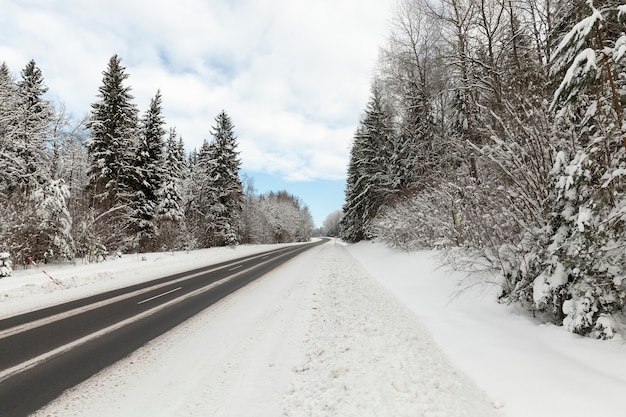 Eine schneebedeckte Straße in der Wintersaison, die Straße ist nach Kälte und Frost gefährlich und rutschig