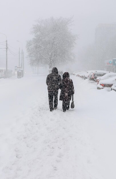 Eine schneebedeckte Straße mit Menschen in einem Sturm, Schneesturm oder Schneefall im Winter bei schlechtem Wetter in der Stadt