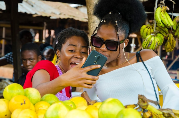 Eine schöne afrikanische Marktfrau und ihre Kunden freuen sich über die Nachrichten, die sie auf ihrem Handy gesehen haben