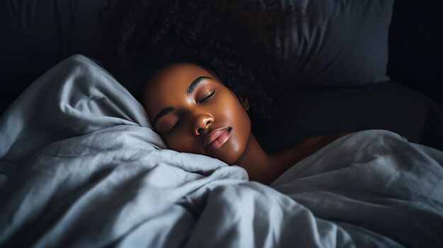 Eine schöne afroamerikanische Frau schläft ruhig unter einer Decke auf einem weichen Bett zu Hause.