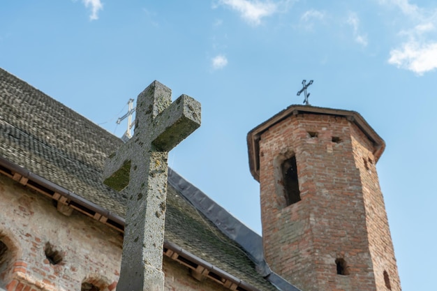 Eine schöne alte Festungskirche aus rotem Backstein vor blauem Himmel Hintergrund Ein großes Steinkreuz auf dem Hintergrund der Backsteinmauer des alten Schlosses