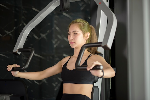 Eine schöne asiatische Fitnessfrau trainiert mit Sportgeräten im Fitnessstudio. Fitness- und Gesundheitskonzept.