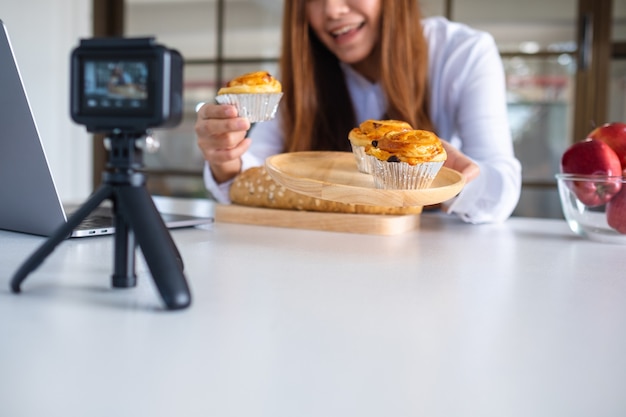 Eine schöne asiatische Foodbloggerin oder Vloggerin, die ein Video mit der Kamera aufnimmt