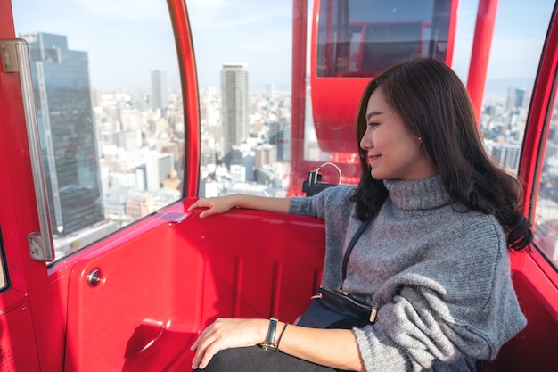 Eine schöne asiatische Frau, die ein rotes Riesenrad in Japan reitet