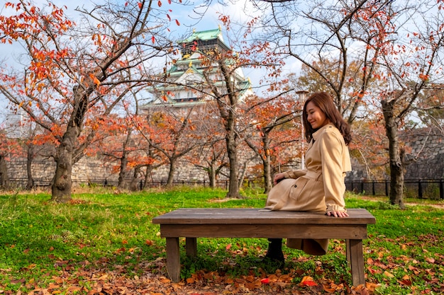 Foto eine schöne asiatische frau genoss es, auf einem holzzweig im herbstgarten zu sitzen