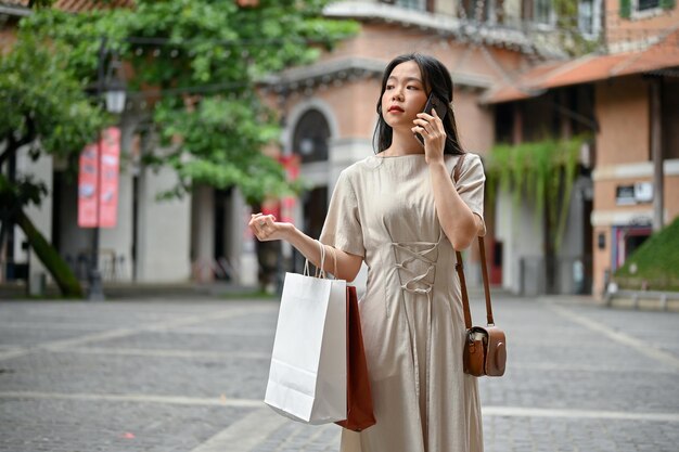 Eine schöne asiatische Frau telefoniert, während sie auf der Straße geht