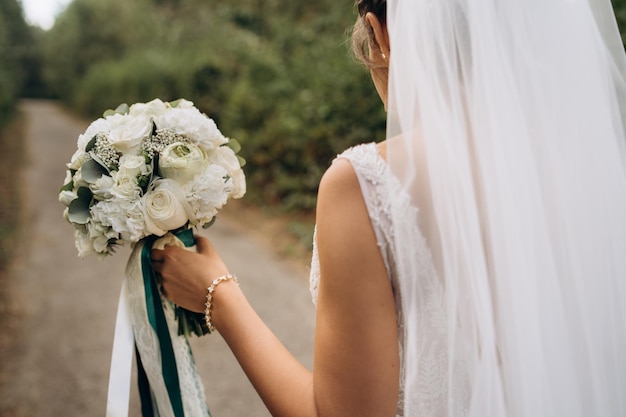 Eine schöne Braut hält ihren Hochzeitsblumenstrauß