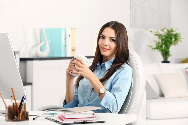 Eine schöne erfolgreiche Frau, die Kaffee im modernen Büro trinkt