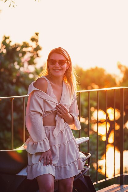 Eine schöne Frau bei Sonnenuntergang steht auf einer Terrasse mit Blick auf das Meer