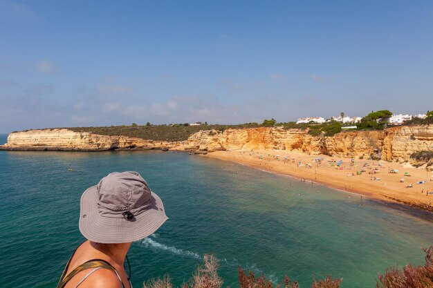 Eine schöne Frau blickt von einer Klippe auf einen portugiesischen Strand