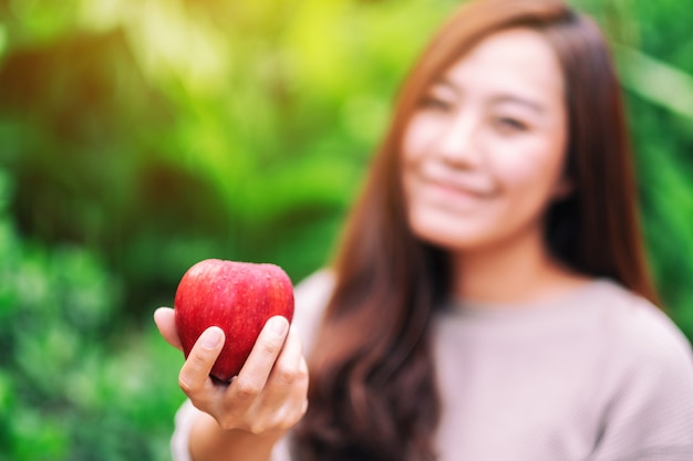 Eine schöne Frau, die einen frischen roten Apfel in der Hand hält