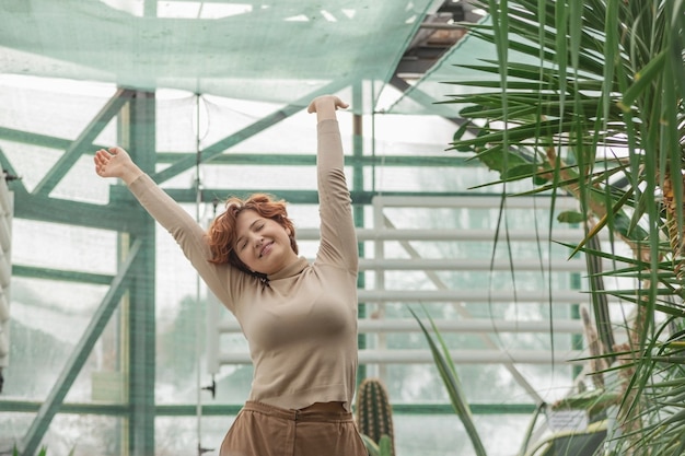 Eine schöne Frau, die genießt, zwischen den grünen Pflanzen zu stehen