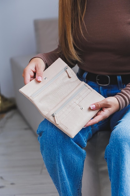 Eine schöne Frau hält eine beige Ledergeldbörse in ihren Händen Kleine Damenhandtasche