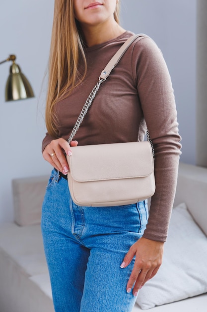 Eine schöne Frau hält eine beige Ledertasche in ihren Händen Eine kleine Damen-Cocktailtasche