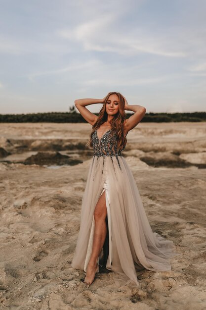 Eine schöne Frau in einem Kleid entspannt sich, tanzt und amüsiert sich auf dem Sand in der Wüste im Freien