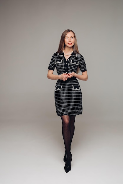 Eine schöne Frau in einem schwarzen Kleid im Studio auf grauem Hintergrund