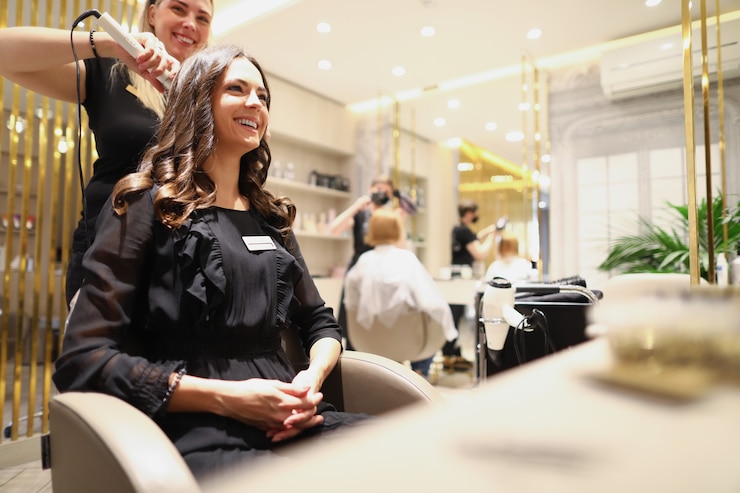 Foto eine schöne frau in einem schwarzen kleid sitzt in einem friseurstuhl und lächelt eine erfahrene