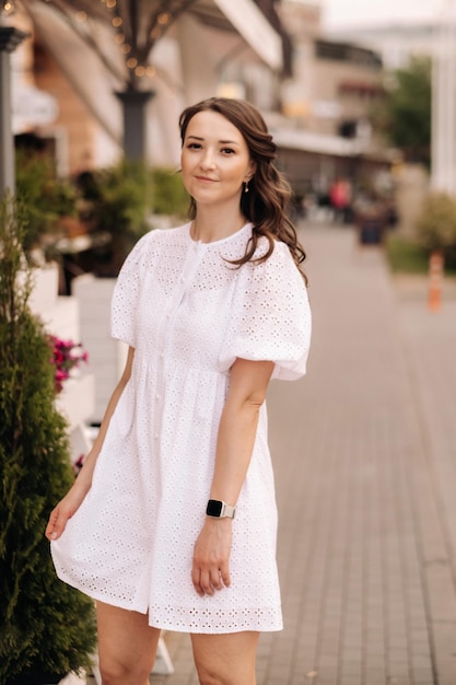 Eine schöne Frau in einem weißen Kleid bei Sonnenuntergang in der Stadt Straßenfotografie am Abend