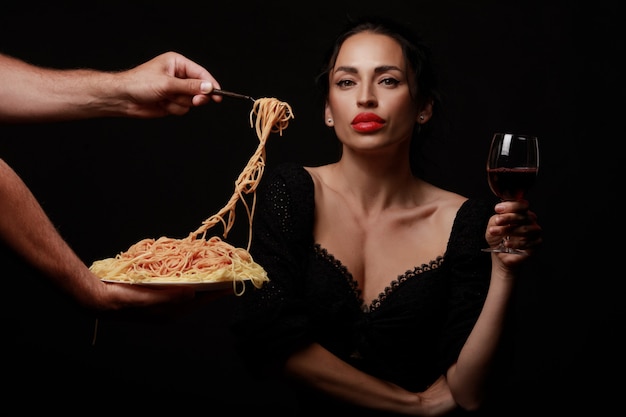 Eine schöne Frau isst Spaghetti und trinkt Wein