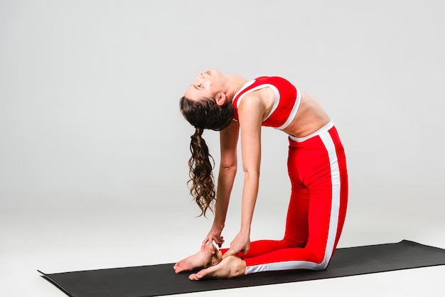 Eine schöne Frau trainiert in einem Yoga-Kurs zur Gewichtsreduktion in der roten Sportbekleidung
