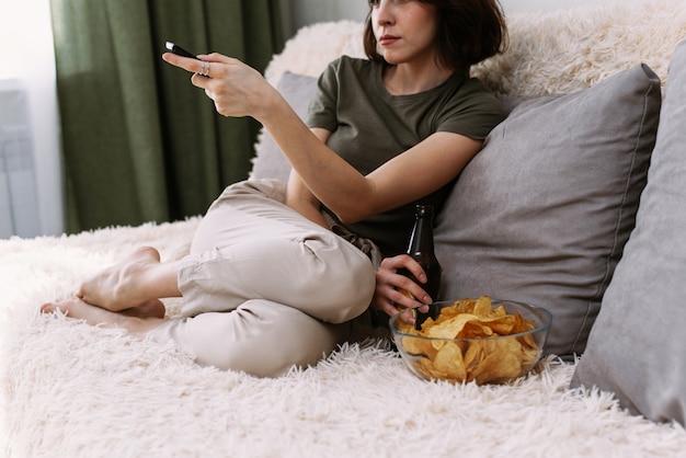 Eine schöne Frau wechselt die Kanäle auf einem Fernseher