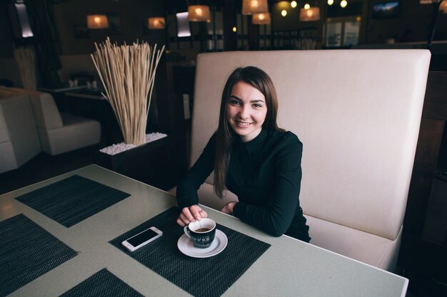 Eine schöne Geschäftsdame in einem schwarzen Hemd, das in einem Café lächelt