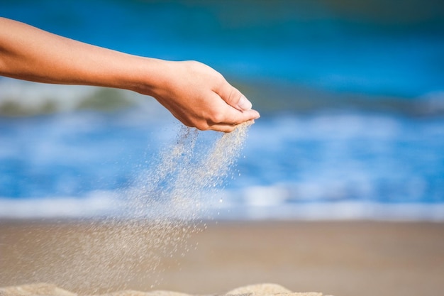 Eine schöne Hand wirft Sand, entspannt sich am Wochenende auf dem Meer